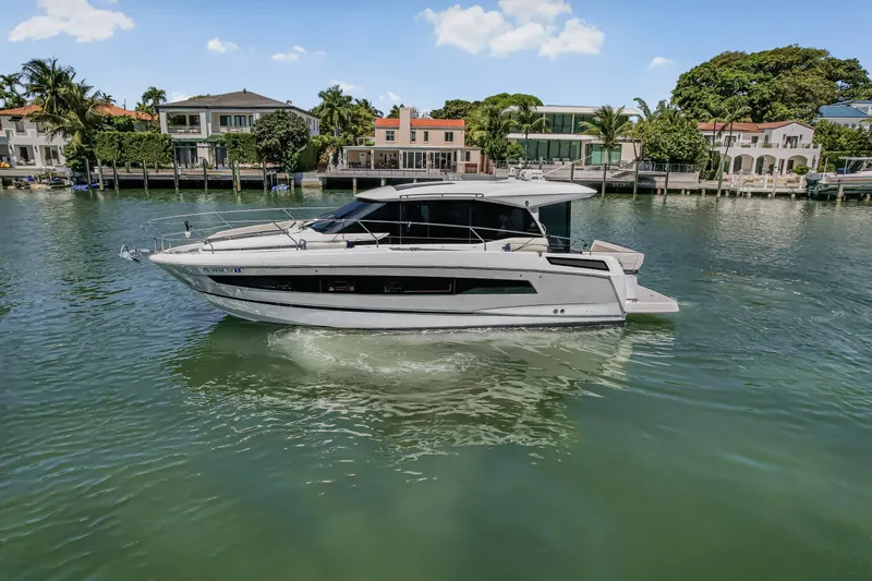 Slide: The Image of 2020 Jeanneau NC 37 yacht cruising on a scenic waterfront with luxury homes. - 3