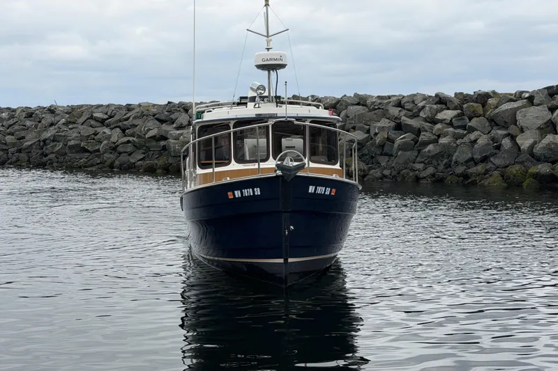 Slide: The Image of 2014 Ranger Tugs R-25 SC boat docked near rocky shoreline. - 2