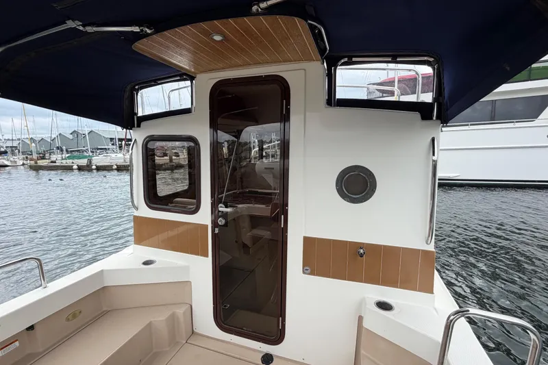 Slide: The Image of 2014 Ranger Tugs R-25 SC boat stern view at marina, featuring cabin entrance. - 21