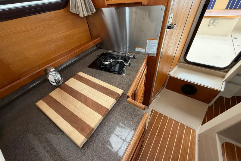 Slide: The Image of 2014 Ranger Tugs R-25 SC galley with stove, cutting board, and wood accents. - 25