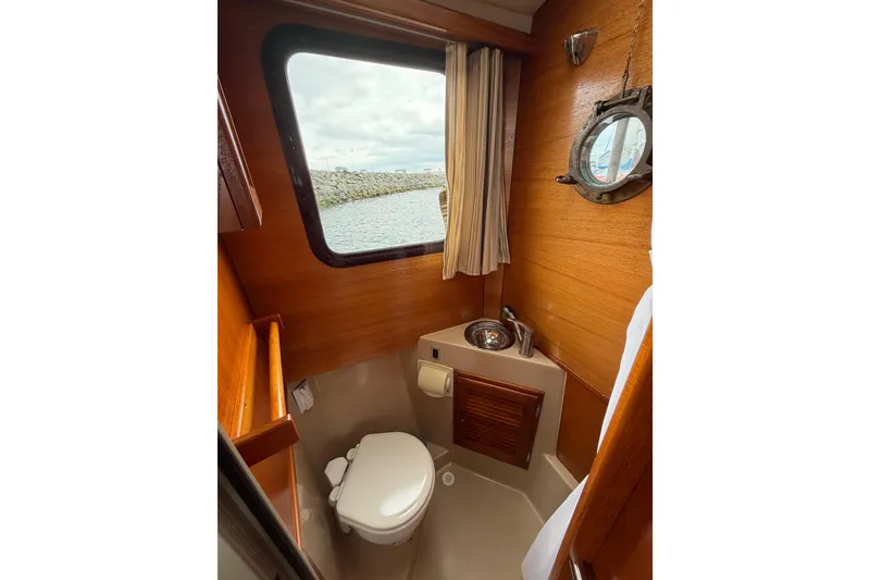Slide: The Image of 2014 Ranger Tugs R-25 SC boat bathroom with wooden interior and porthole window. - 26