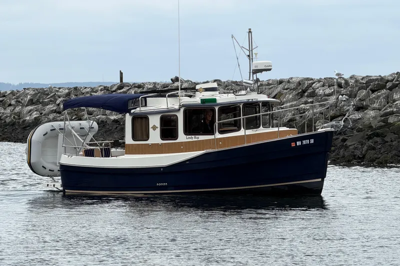 Slide: The Image of 2014 Ranger Tugs R-25 SC boat on water near rocky shoreline. - 8