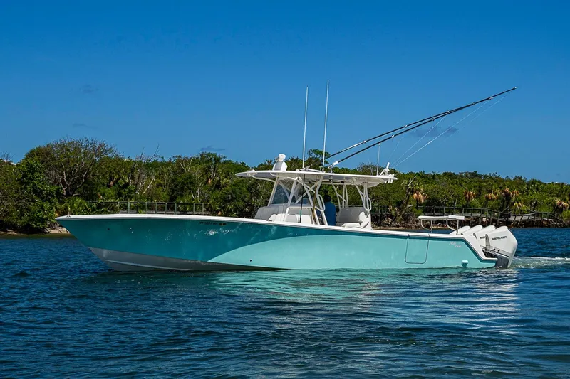 Slide: The Image of 2023 SeaVee 390B boat cruising on a sunny day with lush greenery in the background. - 1