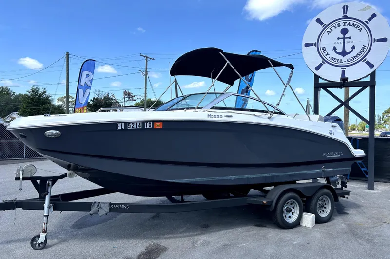 Slide: The Image of 2020 Four Winns HD220 boat on trailer at dealership under clear sky. - 8