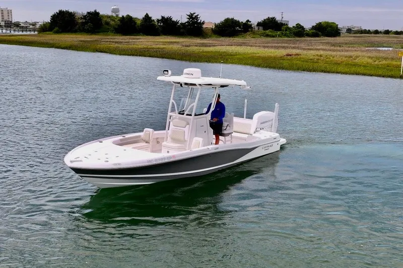 Slide: The Image of 2020 Caymas 26 HB boat cruising on a calm waterway, surrounded by lush greenery. - 1