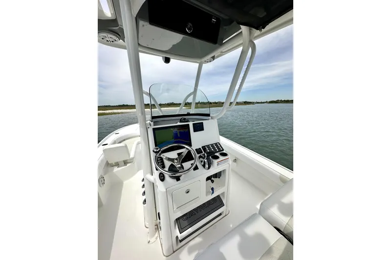 Slide: The Image of 2020 Caymas 26 HB boat console with steering wheel and navigation system on calm water. - 17