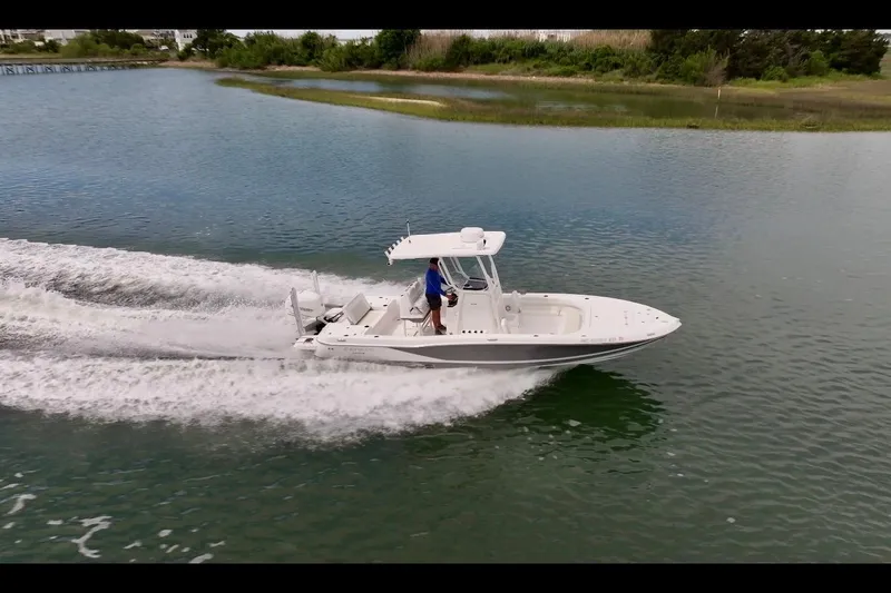 Slide: The Image of 2020 Caymas 26 HB boat cruising on a serene lake with lush greenery. - 2