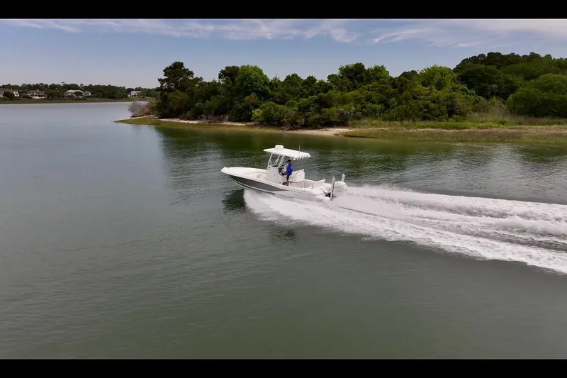 Slide: The Image of 2020 Caymas 26 HB boat cruising on a serene lake with lush green shoreline. - 6