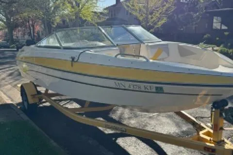 Slide: The Image of 2007 Glastron GT 205 boat on trailer, parked on a sunny residential street. - 1