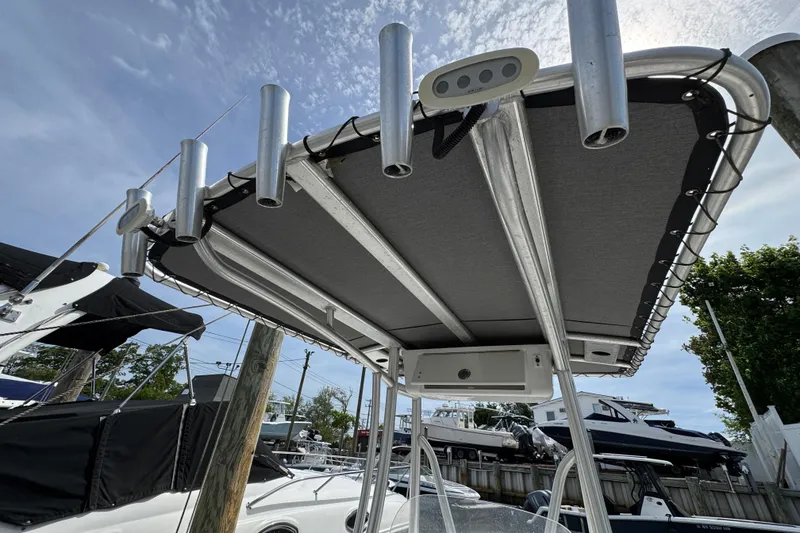 Slide: The Image of Tidewater 198 CC Adventure 2020 boat with T-top and rod holders, docked under clear sky. - 6