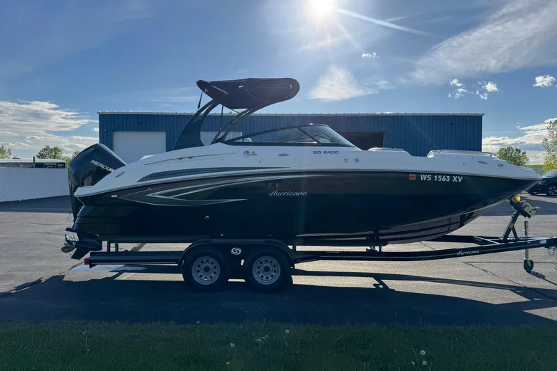 Slide: The Image of 2025 Hurricane SunDeck 2400 OB boat on trailer, parked outdoors. - 2