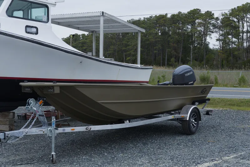 Slide: The Image of 2026 G3 Gator Tough 18 DK boat on trailer, parked beside another boat. - 3