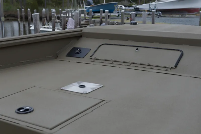 Slide: The Image of 2026 G3 Gator Tough 18 DK boat deck with storage compartments at a marina. - 9