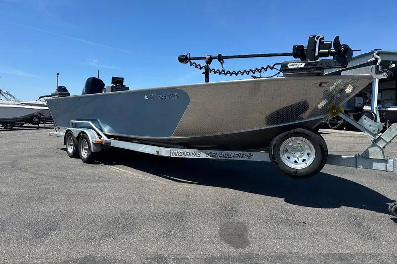 The Image of 2024 Alumaweld Columbia 25 boat on Rogue trailer, parked outdoors under clear blue sky. - 1