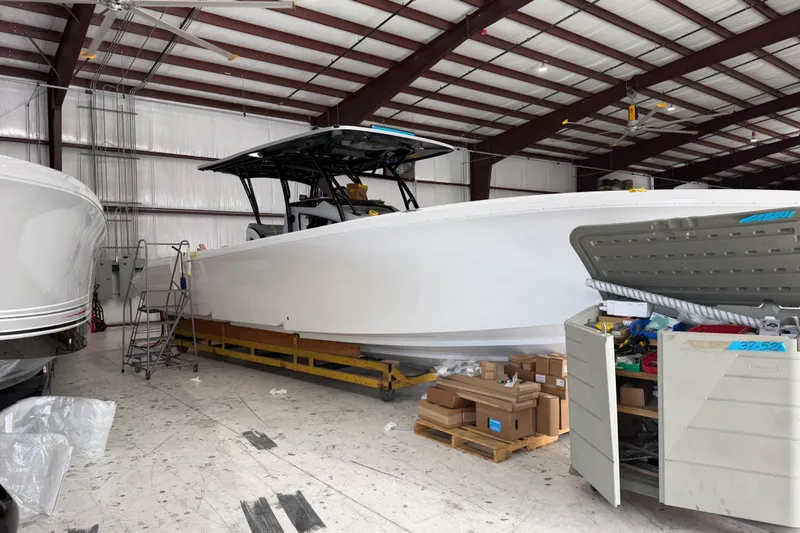 Slide: The Image of 2027 Nor-Tech 390 Sport Center Console boat in a warehouse, surrounded by tools and boxes. - 10