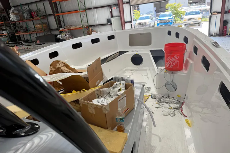 Slide: The Image of 2027 Nor-Tech 390 Sport Center Console under construction in a workshop with tools and materials. - 15