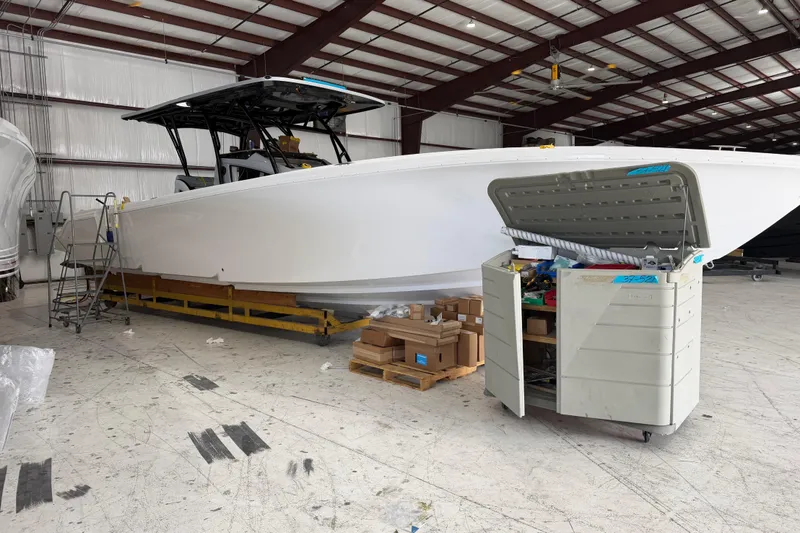 Slide: The Image of 2027 Nor-Tech 390 Sport Center Console boat in a warehouse, surrounded by tools and boxes. - 9