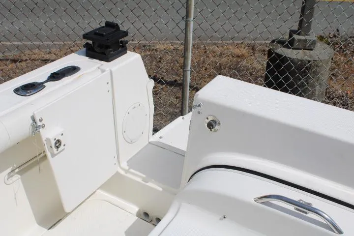 Slide: The Image of 2006 Trophy 2359 Pro boat interior with storage compartments and seating near a chain-link fence. - 15