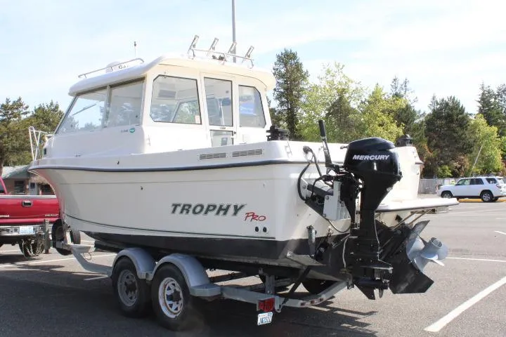 Slide: The Image of 2006 Trophy 2359 Pro boat on trailer with Mercury outboard motor in parking lot. - 3