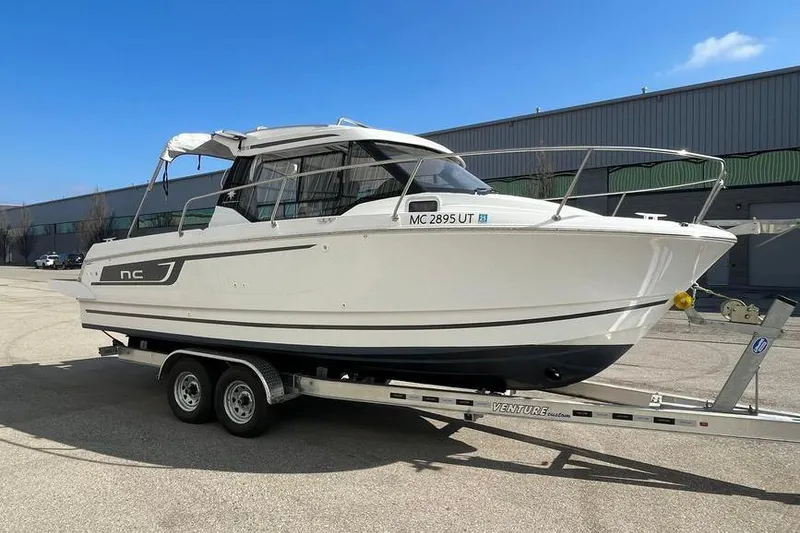 Slide: The Image of 2022 Jeanneau NC 795 boat on trailer, parked outdoors under clear blue sky. - 2