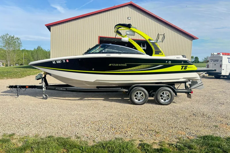 Slide: The Image of 2016 Four Winns TS222 boat on trailer, parked outdoors near a building. - 1
