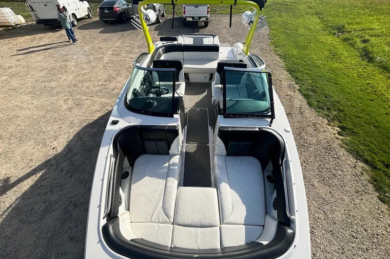 Slide: The Image of 2016 Four Winns TS222 boat interior with seating and open windshield, parked on gravel. - 12