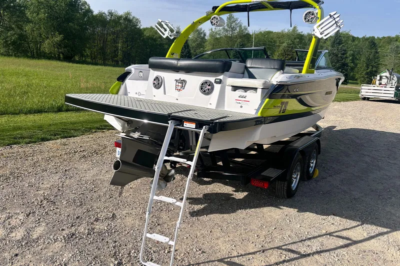 Slide: The Image of 2016 Four Winns TS222 boat on trailer with ladder, parked on gravel near grassy field. - 8