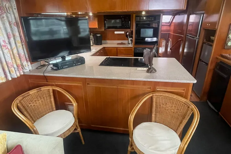 Slide: The Image of 2001 Novatec Islander yacht interior with kitchen, TV, wicker chairs, and modern appliances. - 22