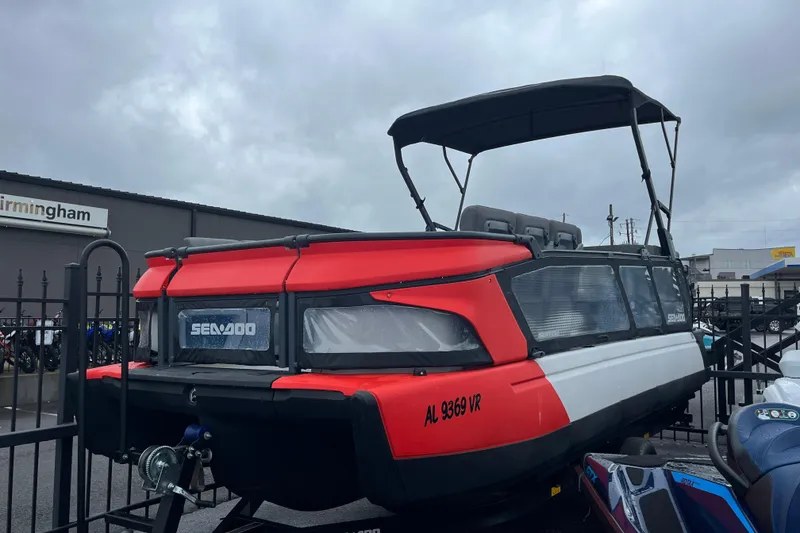 The Image of 2022 Sea-Doo Switch Cruise 21 pontoon boat with red and white design, parked outdoors. - 0