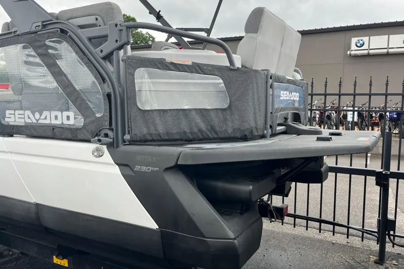 Slide: The Image of 2022 Sea-Doo Switch Cruise 21 pontoon boat, rear view, parked near a fence. - 8