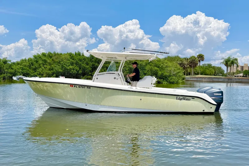 The Image of 2007 Edgewater 268CC boat on calm water, clear sky, lush greenery background. - 0