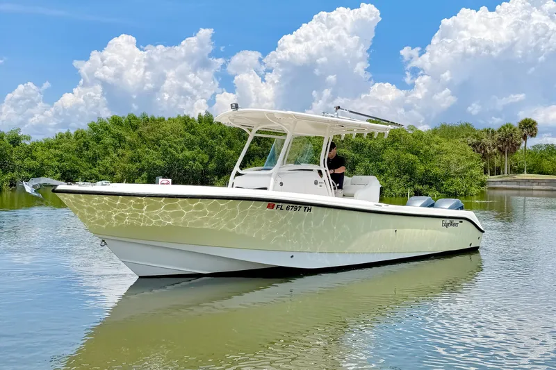 Slide: The Image of 2007 Edgewater 268CC boat on calm water with lush greenery and cloudy sky backdrop. - 8