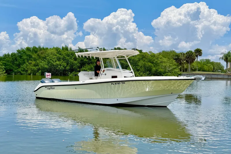 Slide: The Image of 2007 Edgewater 268CC boat on calm water with lush greenery and cloudy sky. - 9