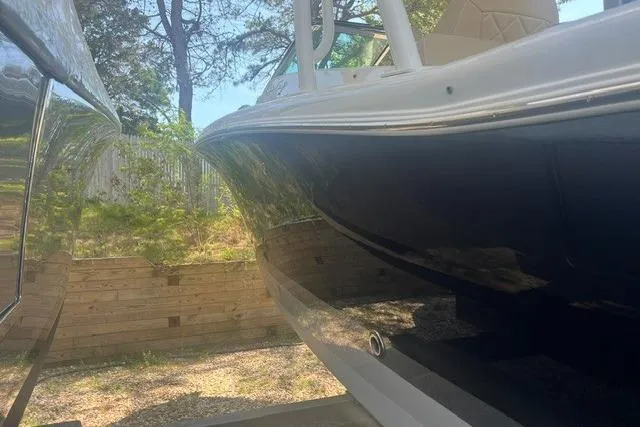 Slide: The Image of 2017 Chris-Craft Calypso 26 boat side view, reflecting sunlight, parked outdoors. - 8