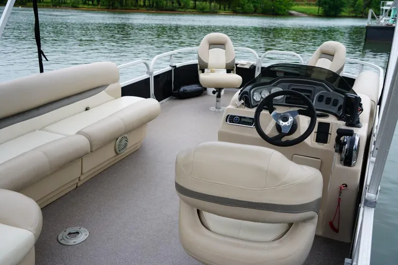 Slide: The Image of 2016 Sun Tracker Fishin' Barge 20 DLX interior with beige seating and steering console. - 8
