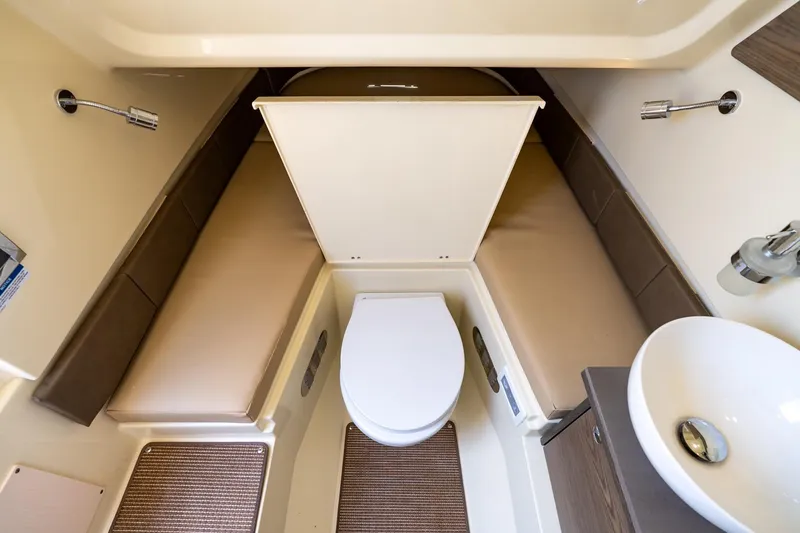 Slide: The Image of 2024 Chris-Craft Catalina 30 cabin interior with toilet and sink, featuring beige seating. - 25