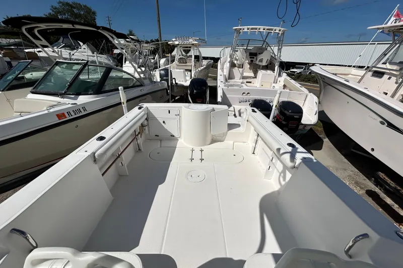 Slide: The Image of 2005 Aquasport 250 Explorer boat with spacious deck, surrounded by other boats in a marina. - 4