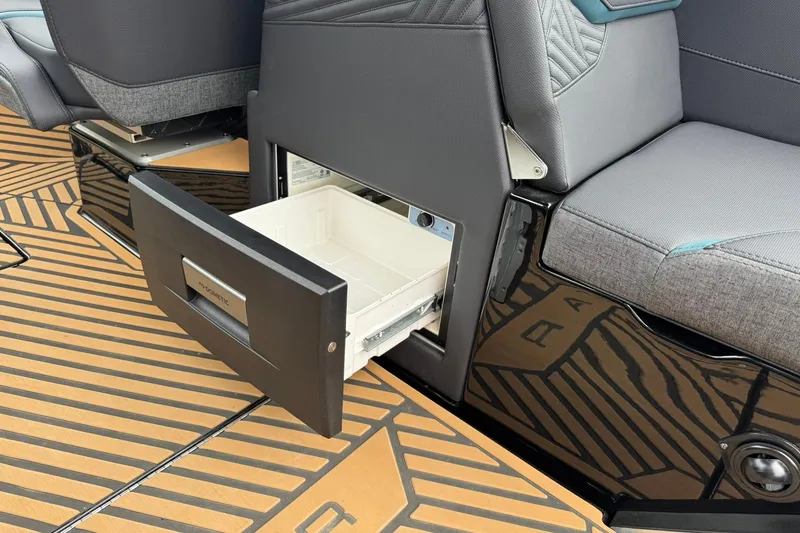 Slide: The Image of 2025 MasterCraft XStar 25 boat interior with open storage drawer, showcasing luxury seating. - 17