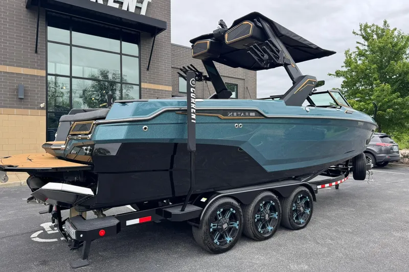 Slide: The Image of 2025 MasterCraft XStar 25 boat on trailer, parked outside a modern building. - 3
