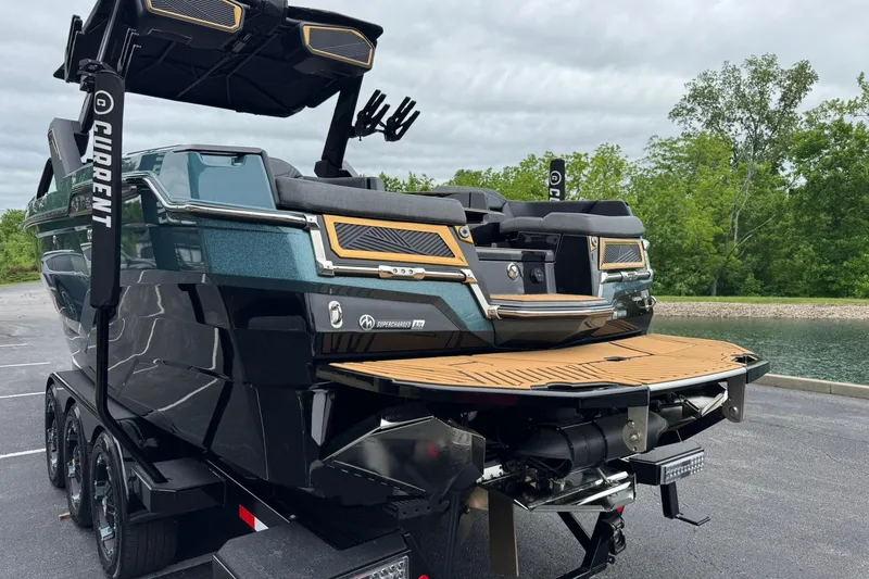 Slide: The Image of 2025 MasterCraft XStar 25 boat with sleek design, parked near a serene lake. - 6