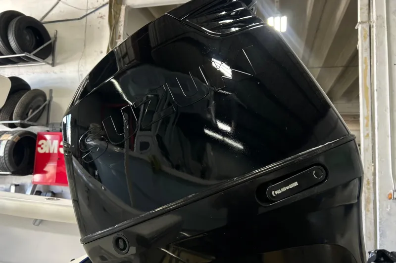 Slide: The Image of Black Suzuki outboard motor in a workshop, near tires and 3M products. - 15
