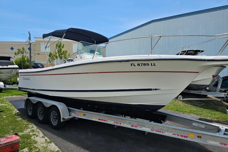 The Image of 1998 Bayliner 2503 Trophy Center Console boat on a trailer, parked outdoors. - 0