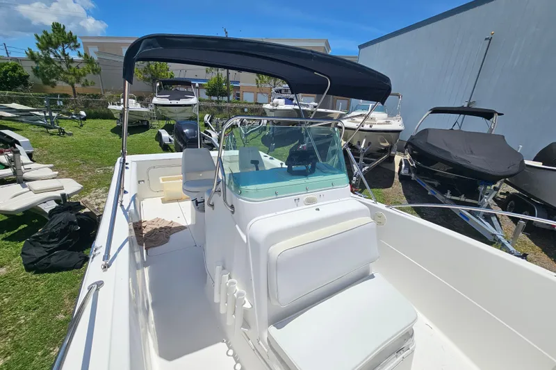 Slide: The Image of 1998 Bayliner 2503 Trophy Center Console boat with canopy, parked outdoors among other boats. - 24