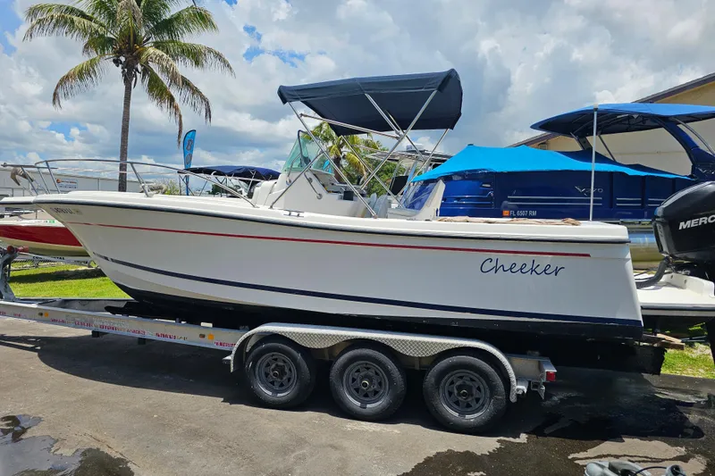 Slide: The Image of 1998 Bayliner 2503 Trophy Center Console boat on trailer, under a palm tree. - 3