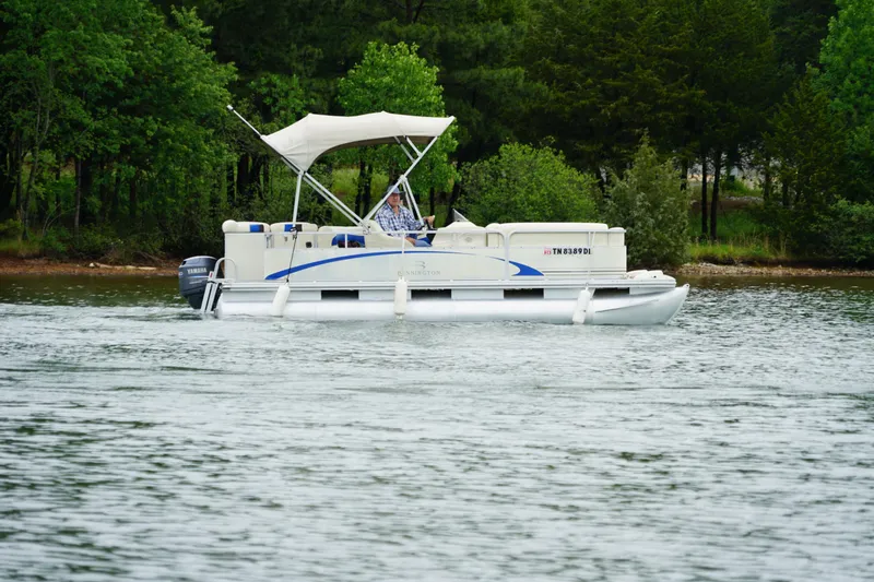 The Image of 2005 Bennington II 207L pontoon boat cruising on a scenic lake with lush greenery. - 1