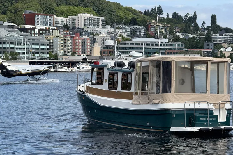 Slide: The Image of 2014 Ranger Tugs R-27 boat on water with cityscape and seaplane in background. - 23