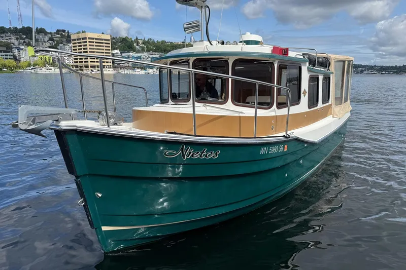 Slide: The Image of 2014 Ranger Tugs R-27 boat on water, green hull, cityscape background. - 26