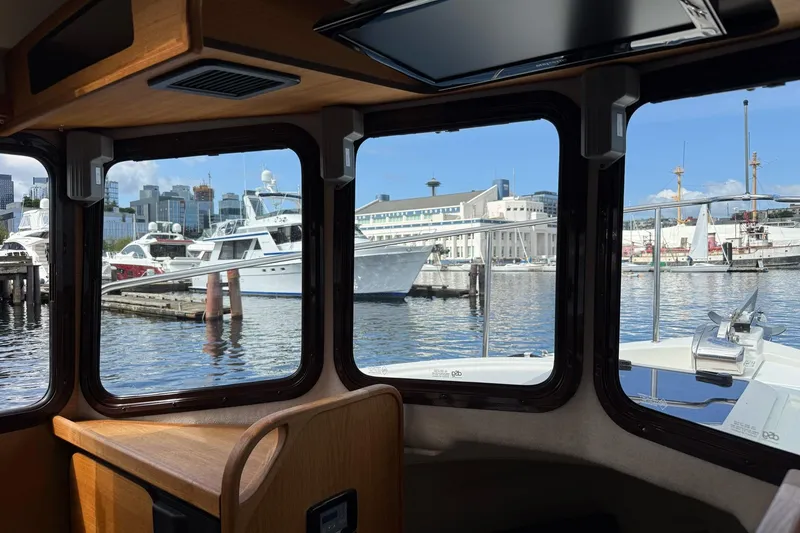 Slide: The Image of Interior view from 2014 Ranger Tugs R-27, overlooking marina with yachts and cityscape. - 28