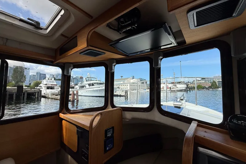 Slide: The Image of Interior view of 2014 Ranger Tugs R-27 boat with marina and cityscape outside. - 29