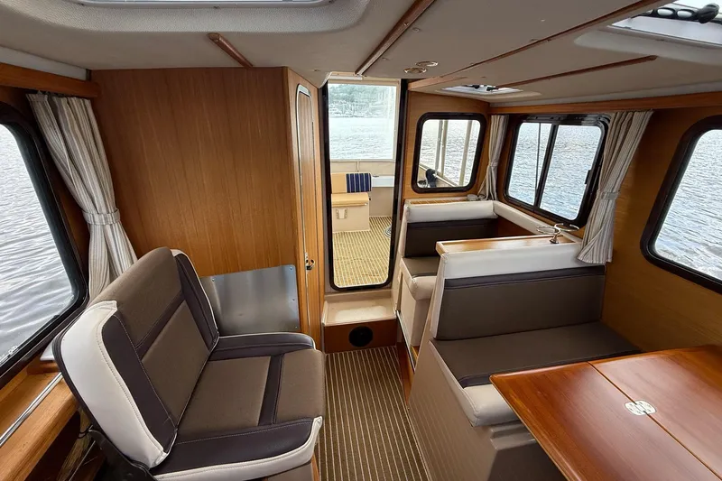 Slide: The Image of Interior of 2014 Ranger Tugs R-27 boat with seating and windows overlooking water. - 48